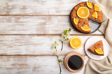 Orange cake and a cup of coffee on a white wooden background. Top view, copy space.