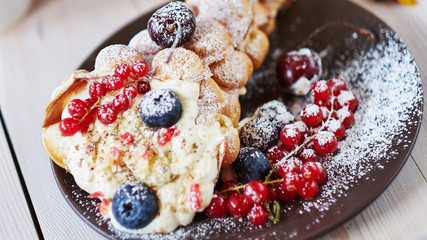 Delicious sweet bubble waffles with berry on a wooden table