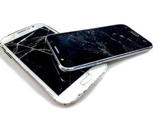 Two smartphones positioned one above the other, with the glass of the display broken, positioned on...