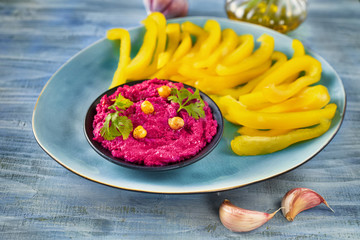 Blue platter of yellow paprika sticks with bright red dip