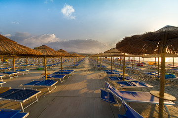 Fototapeta na wymiar Beach umbrellas and lounge chairs on the sandy shore in Sardinia