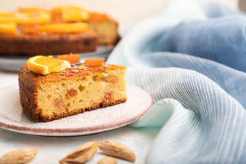 Orange cake with almonds and a cup of coffee on a white concrete background. Top view, selective focus.
