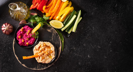 Bright and colorful assorted fresh vegetables platter with various hummus dips