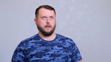 Tired fat bearded man in a blue T-shirt rolls his eyes. He was tired of work or tired of listening to his wifes conversation