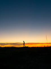 Fototapeta na wymiar Man walking at sunset silhouette 