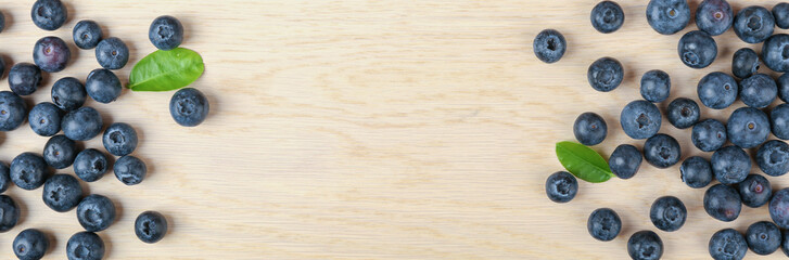 blueberry berries with green leaves on wooden background flat lay with copy space