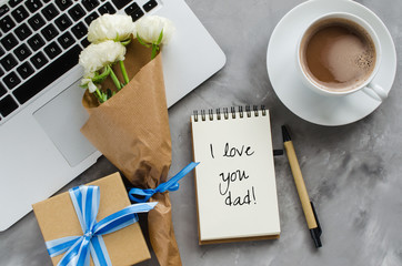 Fototapeta na wymiar Inscription I Love You Dad, laptop computer, gift box, coffee and flowers. Father's day or birthday concept.