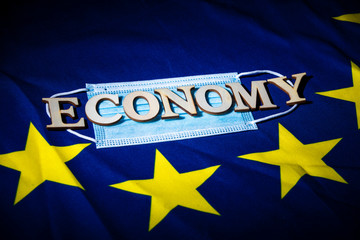 flat face mask on a European flag with wooden letters forming words to create a concept