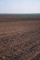 Plowed endless farm field. The fertile land of the agricultural sector. Sowing on black soil in the garden. Industrial stock theme