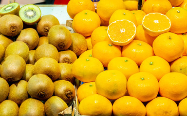 Farm fresh harvest fruits, ripe kiwi & oranges on store shelf display at Farmers Market for sale. Whole and sliced cut agricultural produce from local farmers. Healthy raw vegan/ vegetarian food diet.