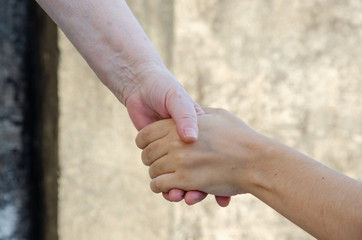 close up on handshaking at daylight outdoor, with old and young skin