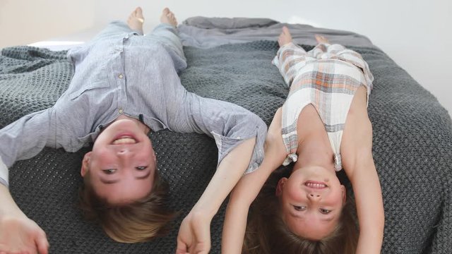 Siblings laying on bed shaking their heads