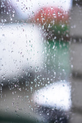 Obraz premium Window overlooking a rainy street. Gloomy evening weather with a view of the road. Drops on glass and bokeh from cars. Stock background for design