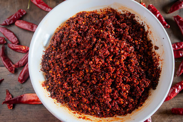 Dried chilies and chili sauce are on the wooden table