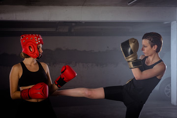 Strong sportswoman doing her high leg kick on her female boxer buddy