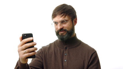 Confident businessman holding smartphone in hand and typing text message. Bearded man using cell phone on white background