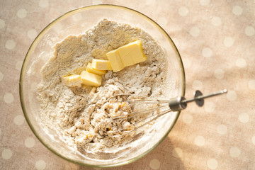 the process of preparing dough for pancakes with ingredients on a light table, in a transparent bowl of flour and butter