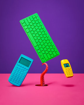 Calculator Keyboard and Cell Phone Floating and Balancing on Pink Surface with Purple Background