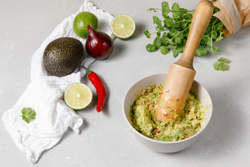 Mexican sauce guacamole in a mortar with ingredients