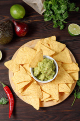 Mexican avocado sauce guacamole served with nachos on a wooden background