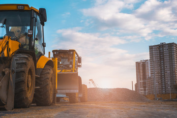 Building site with high-rise block under construction in an urban environment dominated by a large industrial crane silhouetted against a cloudy blue sky