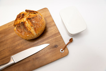 Flat lay packshot chleb z deską, nożem i maselniczką bochenek domowego pieczywa na dużej desce do krojenia