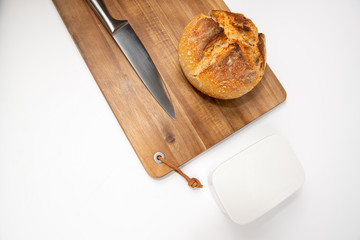 Flat lay packshot chleb z deską, nożem i maselniczką bochenek domowego pieczywa na dużej desce...