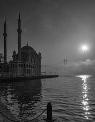 Naklejka premium Ortakoy Mosque and Bosphorus Bridge in Istanbul, Turkey. Dramatic sky. The 15 July Martyrs Bridge in a fog