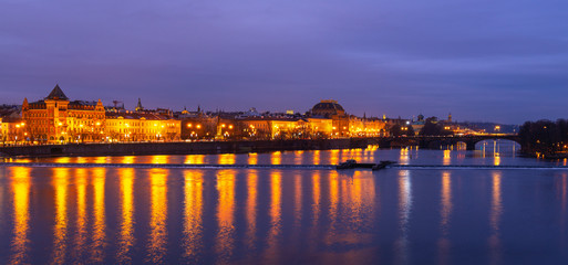 Fototapeta na wymiar Panorama of historic buildings facades reflection in the Vltava river during the blue hour, Prague, Czech Republic.