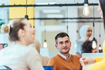 Team working on a digital project. Group of coworkers working in a startup business environment. Employees having fun in a modern office.