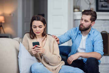 Modern couple at home. Man and woman concentrated on messaging with smartphones, ignoring each other and spending time on social media.