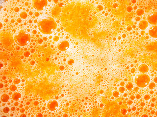 Texture of orange and carrot juice with bubbles.
