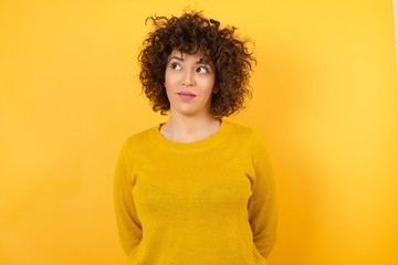 Photo of cheerful positive cute pretty nice girl wearing yellow sweater, looking aside into empty space thoughtful isolated over yellow background