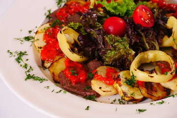 Grilled meat and vegetables, sliced, garnished with tomatoes and lettuce leaves