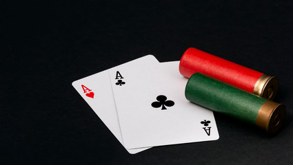 Fototapeta na wymiar Playing cards and two shotgun cartridges lie on a black background