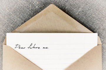 "dear future me" is written on white lined paper, which lies in an open craft envelope. The letter lies on linen cloth
