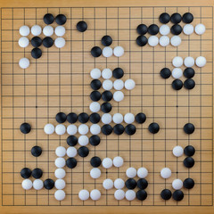 Traditional asian (Chinese) game go - black and white stones lie on the game board (goban), top view, flat lay, square