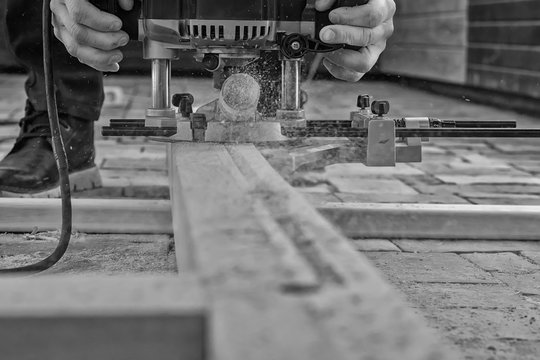 old manual milling cutter (frezer) on wooden board in hands of joiner, black and white photo