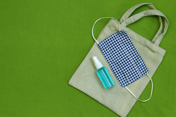 
DIY fabric face mask ,hand sanitizer spray and cloth bag on green background. Concept for the new normal or new lifestyle after COVID-19 Coronavirus pandemic. 