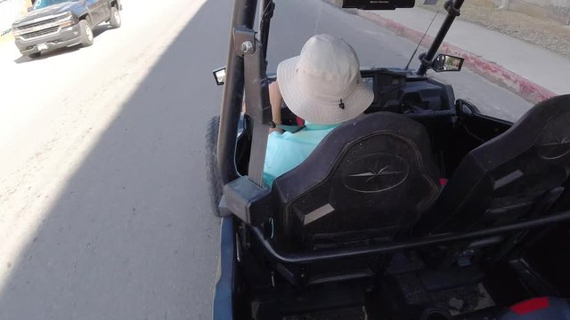 LOS CABOS MEXICO-2019: Guy Wearing A White Hat In A Black Golf Cart Stuck In Traffic On A Hot And Sunny Day