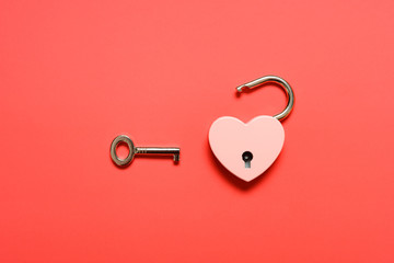 unlocked heart shape padlock with key on a red background