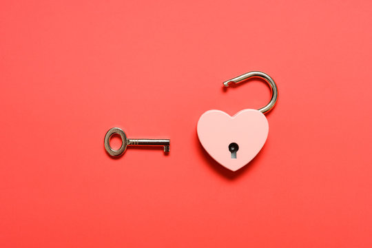 unlocked heart shape padlock with key on a red background
