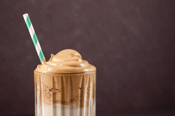 Dalgona coffee in a tall transparent glass, close-up. Popular Korean drink with foam of instant coffee