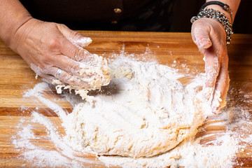 Manos amasando comida tipica sobre mesa de madera.