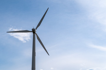 Fototapeta premium Wind turbine in Maple Grove, Minnesota, against a blue sky with clouds in a park