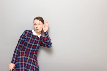 Portrait of intrigued girl placing hand near ear and eavesdropping