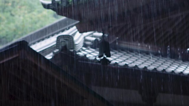 Torrential rain falling on the traditional Japanese roof of a buddhist temple