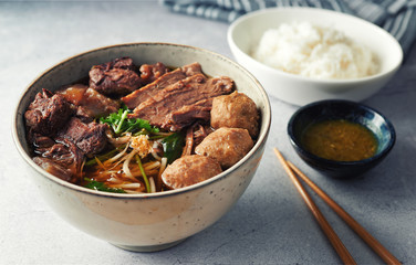 Braised Beef and Meat Ball vegetable Soup with jasmin rice on concrete table