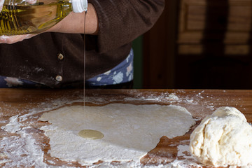 Manos poniendo aceite sobre masa para cocinar comida tradicional 