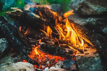 Vivid smoldered firewoods burned in fire close-up. Atmospheric warm background with orange flame of...